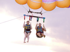 Laughter and joy lifting into the air for a parasail adventure over Roanoke Sound.