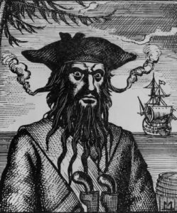 An illustration of Blackbeard the pirate with a ship in the background