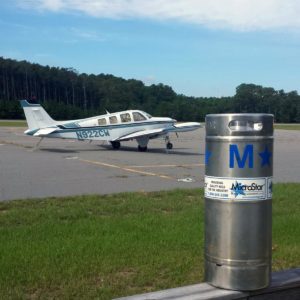 A keg sits with a plane in the background