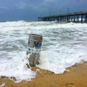 a keg that will soon fly at the annual Kitty Hawk Kites OBX Brewtag sits in the sand as waves crash in to it here at the Outer Banks