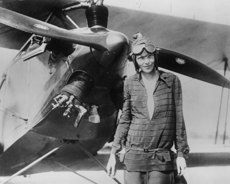 Amelia Earhart in front of her bi-plane