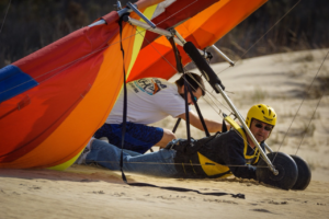 A man and a hang gliding instructor doing a hang gliding lesson on the sand at the Outer Banks