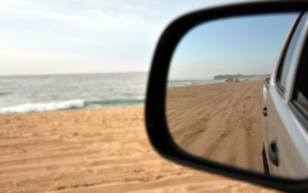 Beach in sideview mirror of 4x4 vehicle