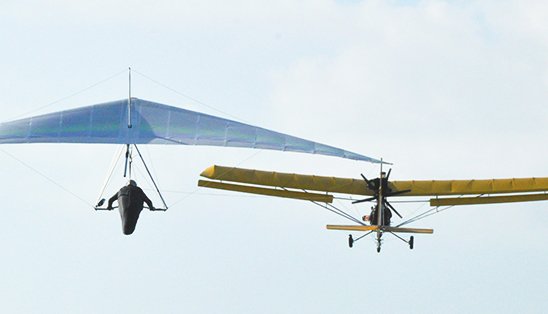 Hang glider being towed to altitude by an ultralight airplane